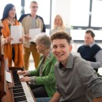 A group of seniors with young teacher singing together at choir rehearsal.